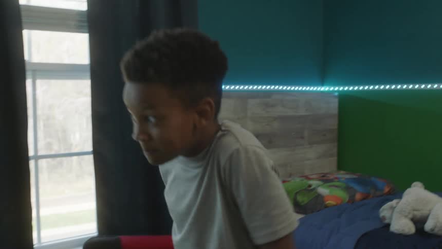 Two young brothers playing with a ball in a home bedroom