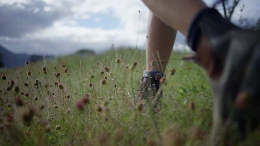 Person wearing socks and hiking boots walking around at an empty field