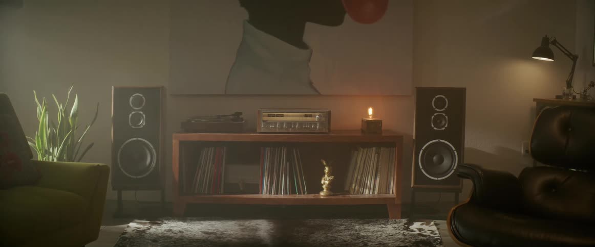 A record player sits on a wooden table filed with albums