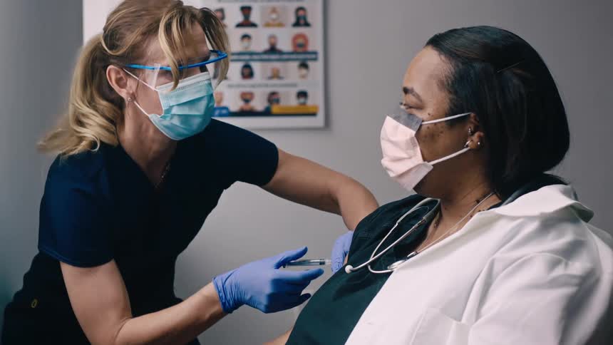 Nurse vaccinating a black woman for coronavirus