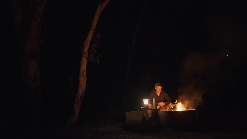 A man is sitting near the campfire at night