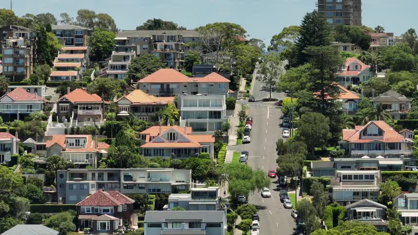 Traffic drive up and down incline through neighborhood of large homes