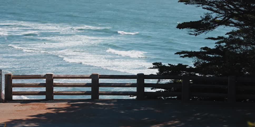 Fenced walkway overlooks waves rushing to shore
