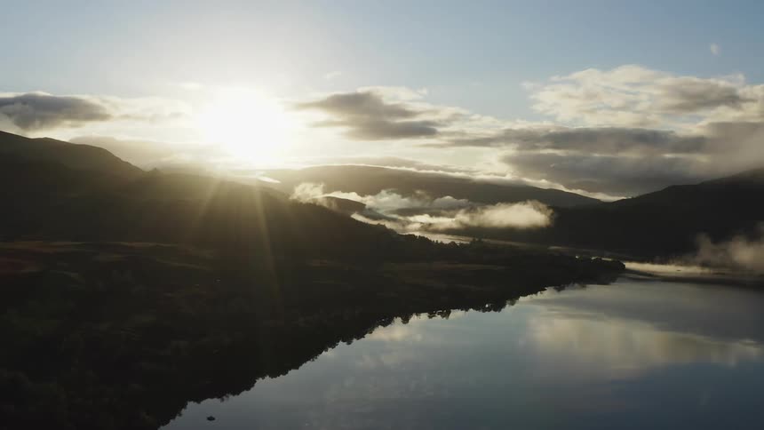 The sun is rising on the lake