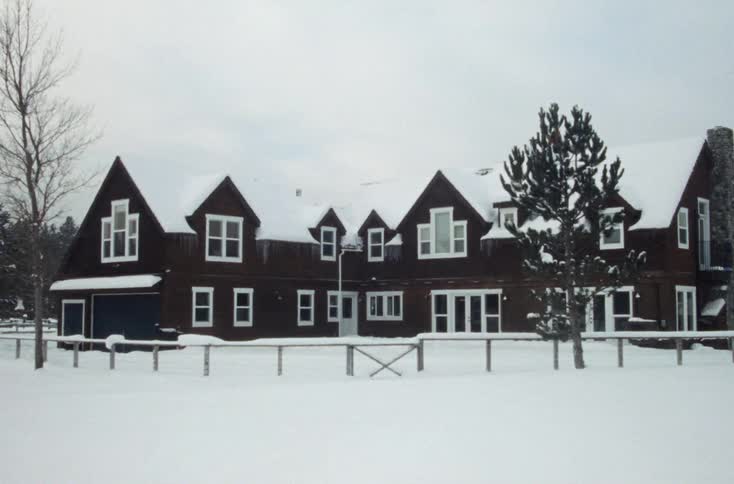 A thick blanket of snow covers the ground and roof on a rural property