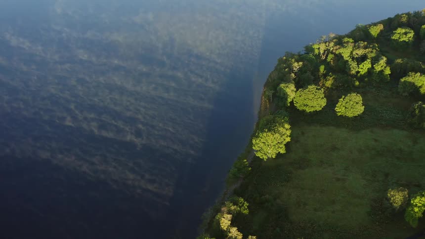 A sunrise over a green forest next to a misty body of water