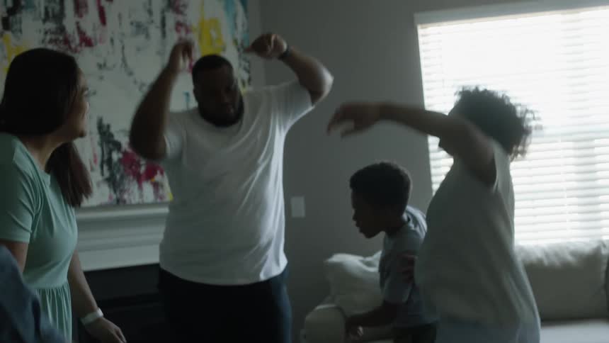 Black family dancing around having fun and partying at the living room