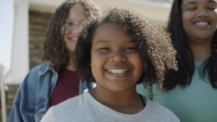 A group of people are standing outside a home and smiling