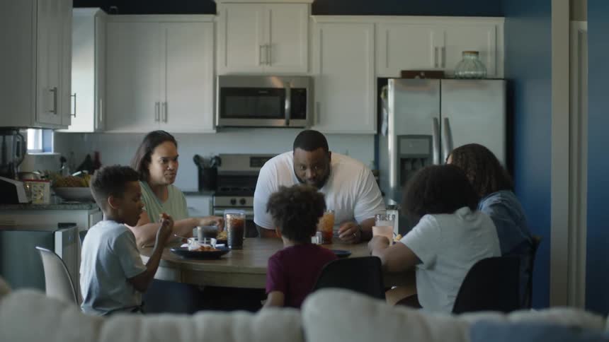A man sits down for dinner with his family at home