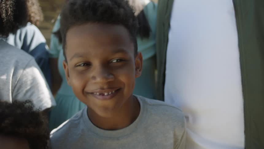 A young boy who is missing a tooth smiles while posing for a family portrait