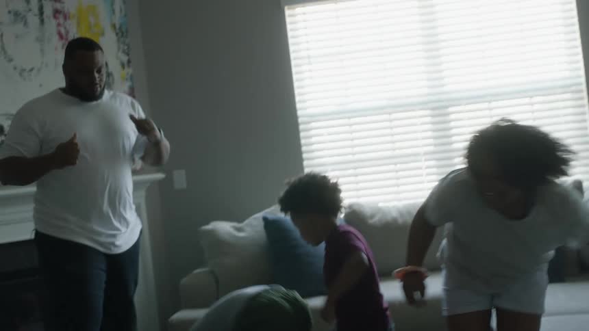 Parents dance around their living room with their kids