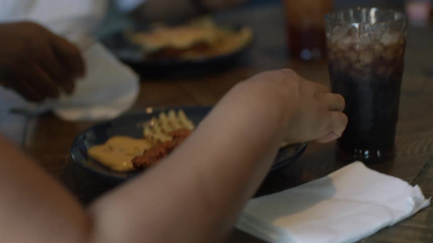 Family sits around dining table eating and talking