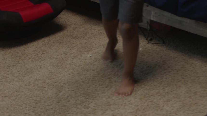 A boy chases after a ball in his bedroom