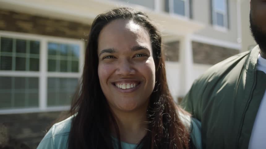 A woman is standing next to a man and smiling for a picture