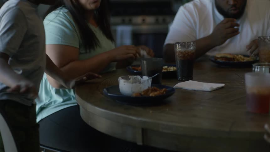 Mother smiles at son as family eats at dinner table