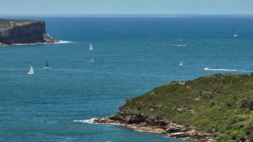 A speedboat moves past sailboats dormant in the sea