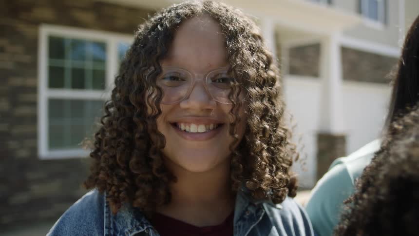 Smiling woman stands in front of home with family
