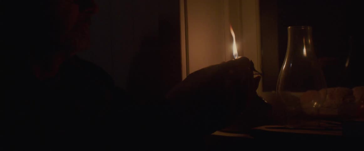 White old man lighting a candle placed next to a window