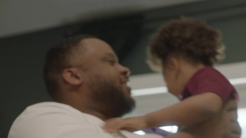 A man picks up his son during a video call on his laptop