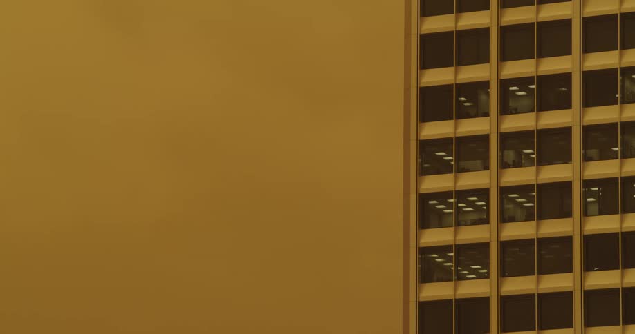 Yellow tinted footage of the facade and windows of an office building in the city