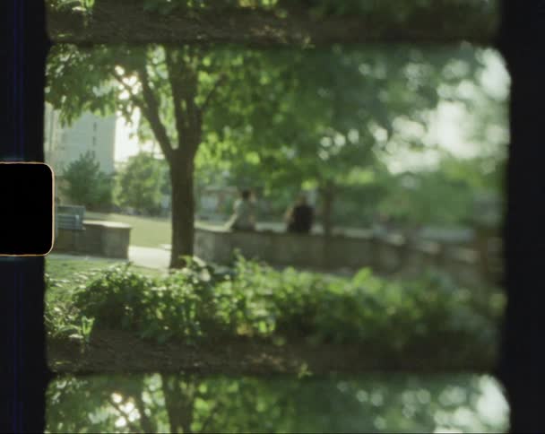 Two people sit on brick wall in park near building