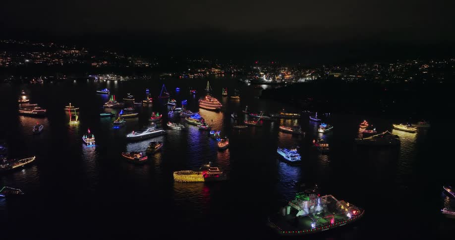 A flotilla of decorated boats gather together by the shore to sing Christmas carols