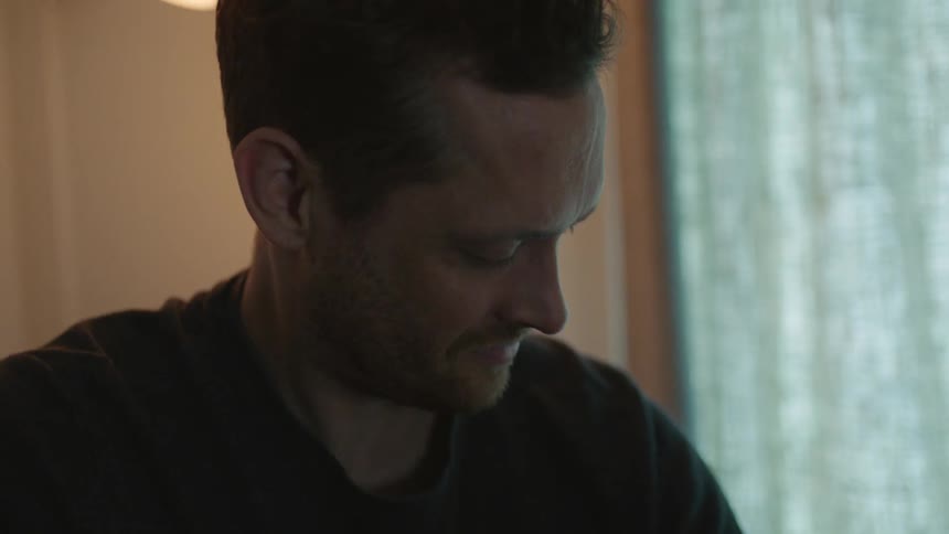 Happy father holding a baby on his arms inside a dimly lit room at home
