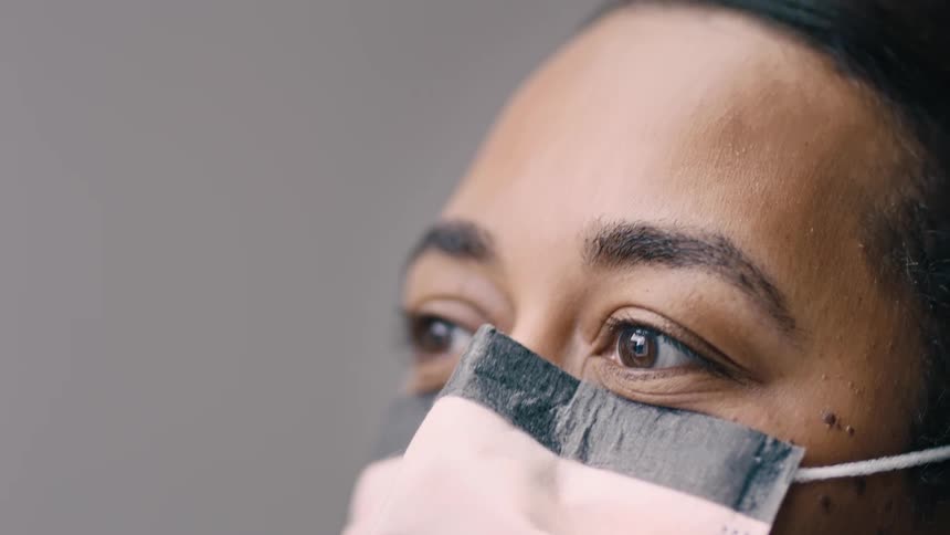 Black woman looking around while wearing a pink mask