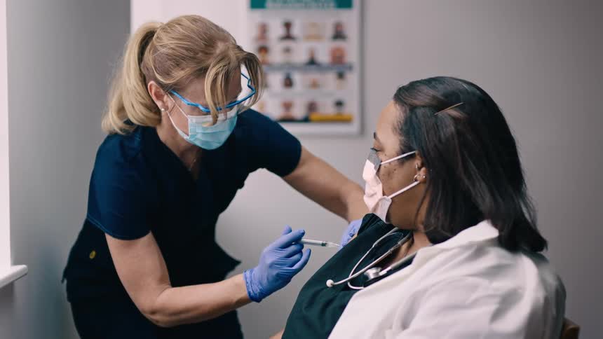 Black woman receives vaccine in the doctors office