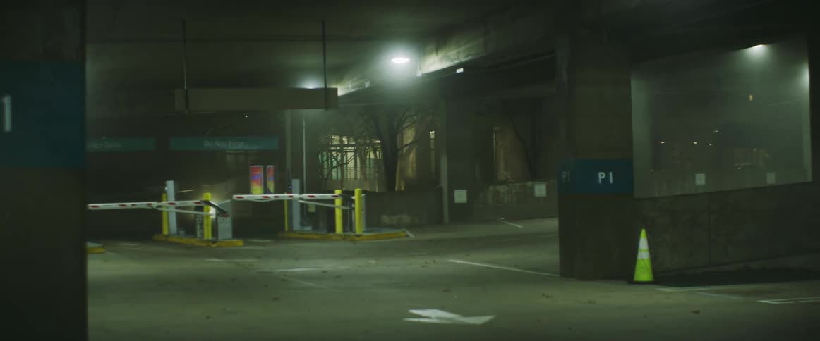 Overhead lights shine on the gates of a parking garage