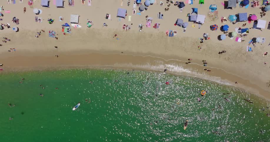 People lounge on the beach and swim in the ocean