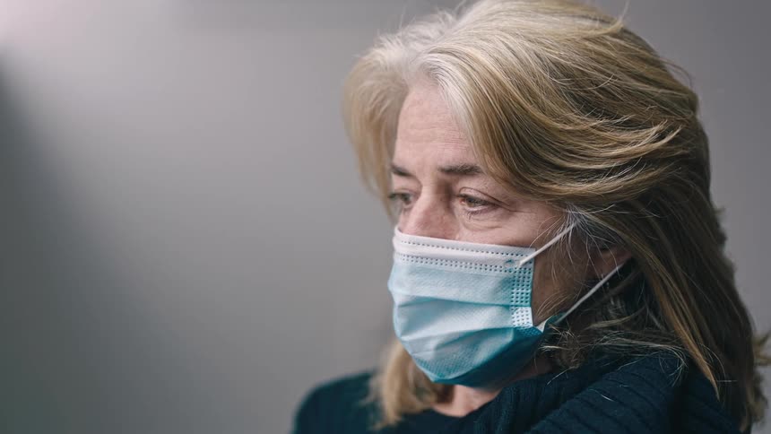 Woman wearing a face mask looks at a nurse filling a syringe