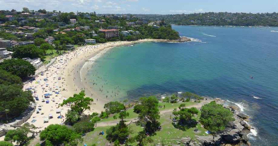 An aerial view of a body of water and a beach filled with people and umbrellas