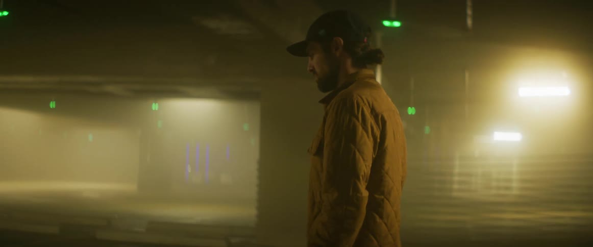 A man walks through a upper level in a parking garage at night