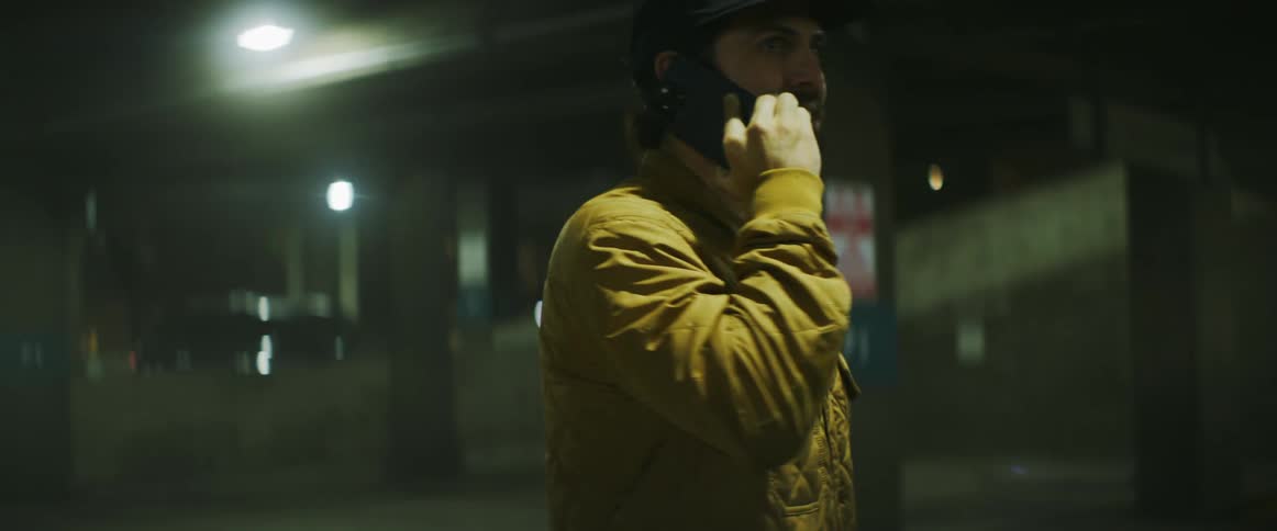 Man stands talking on mobile phone at night in parking area