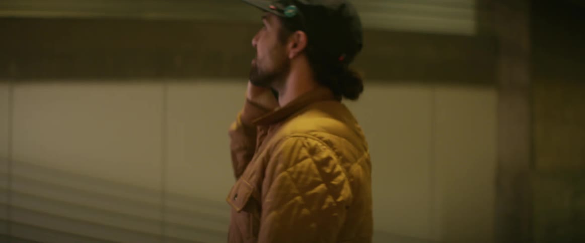 White man standing alone at a parking lot talking on his phone and looking around