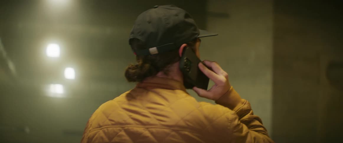 White man talking on the phone while standing in the middle of an empty parking lot