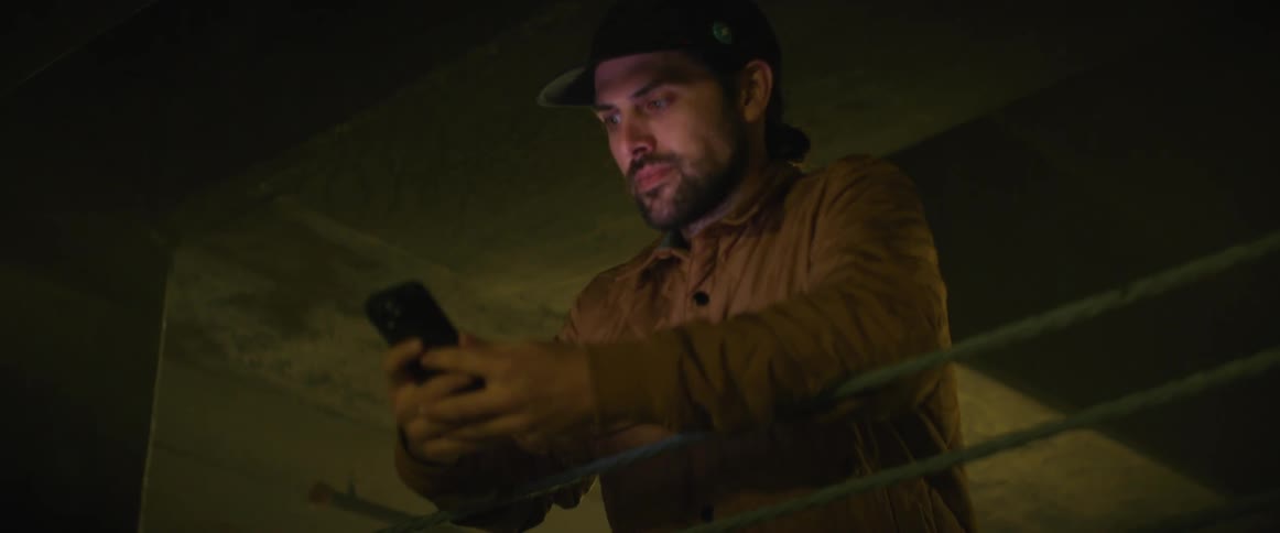 A man looks at his phone in the parking garage