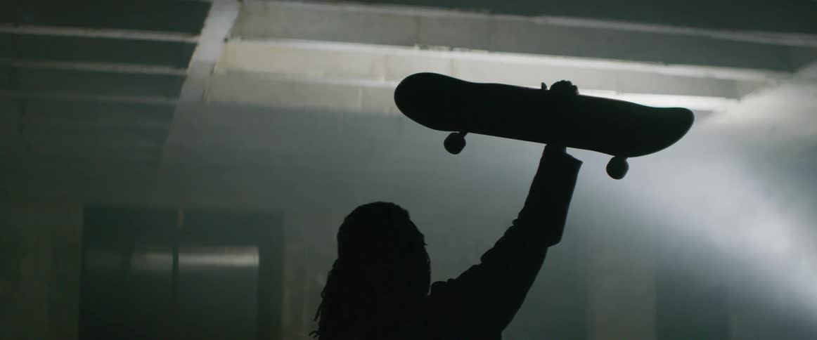 A man has his skateboard lifted above his head