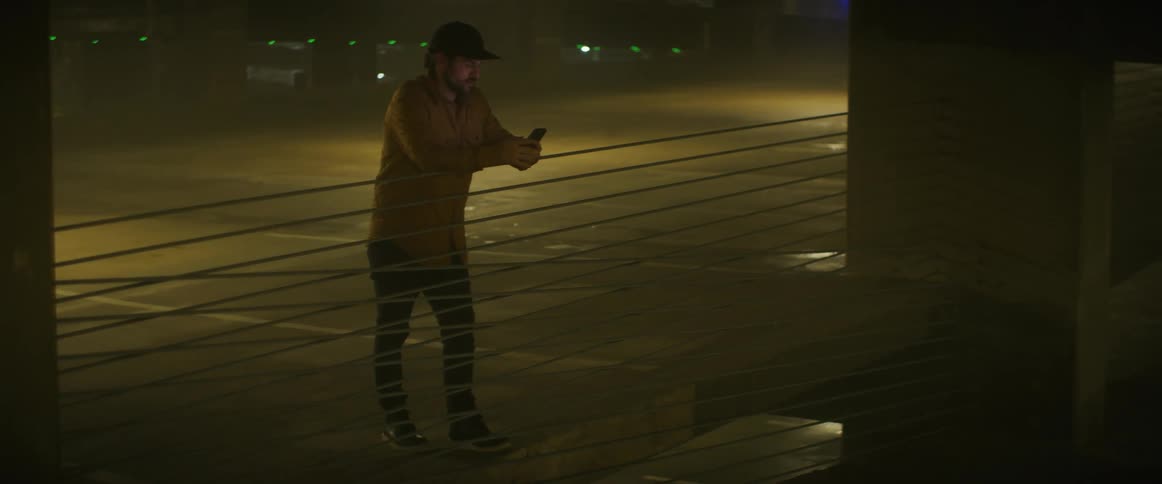Man stands near rail in parking garage using a mobile phone
