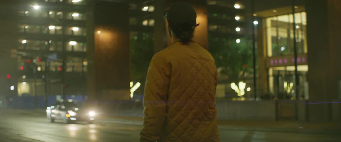 Man walking alone in the sidewalk and looking around at the middle of a big city