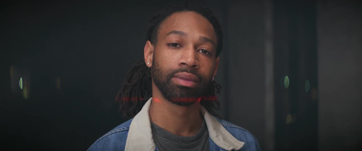 A red light shining over a mans face while he stands for a portrait indoors