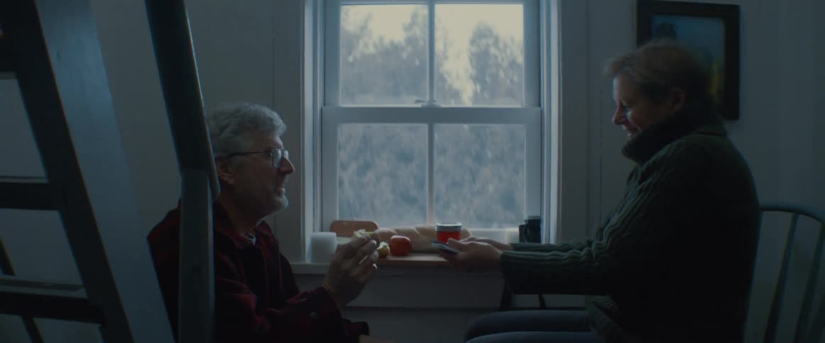 Elderly couple eating near the windowsill at home playing card tricks