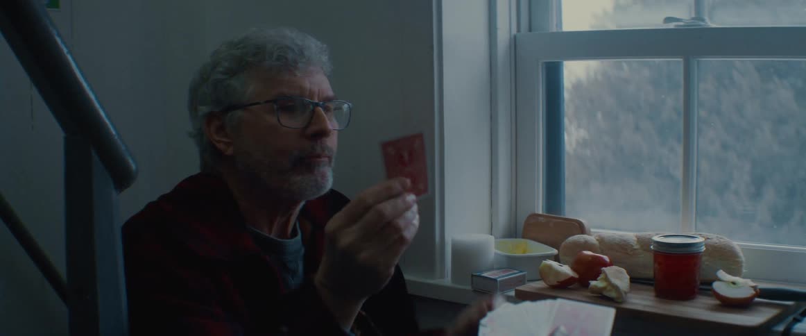 Two men are eating and playing cards