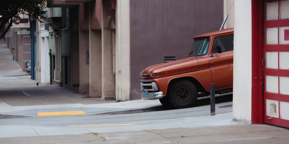 Vehicle sits in alley near street as bird moves across sidewalk