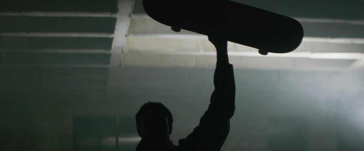 A man lifts the skateboard above his head