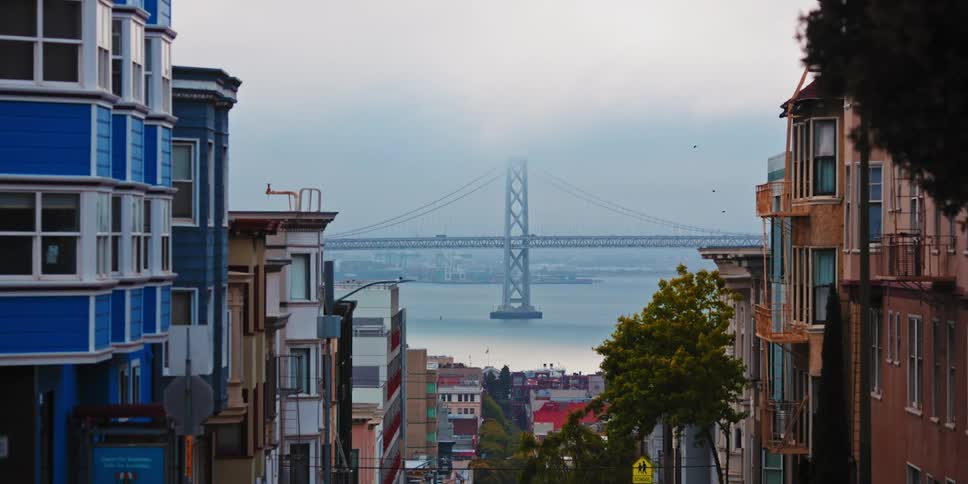 Apartment buildings sit along a hill with views of the coast and a bridge