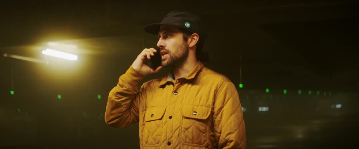 A man paces and walks as hes talking on a phone in a parking garage