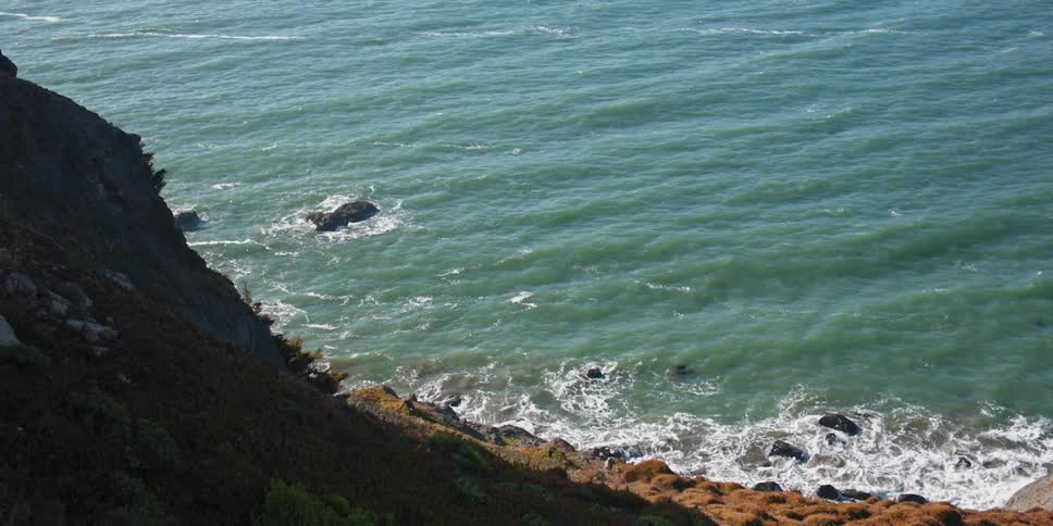 Gentle ocean waves crashing over and around the rocks on the coast
