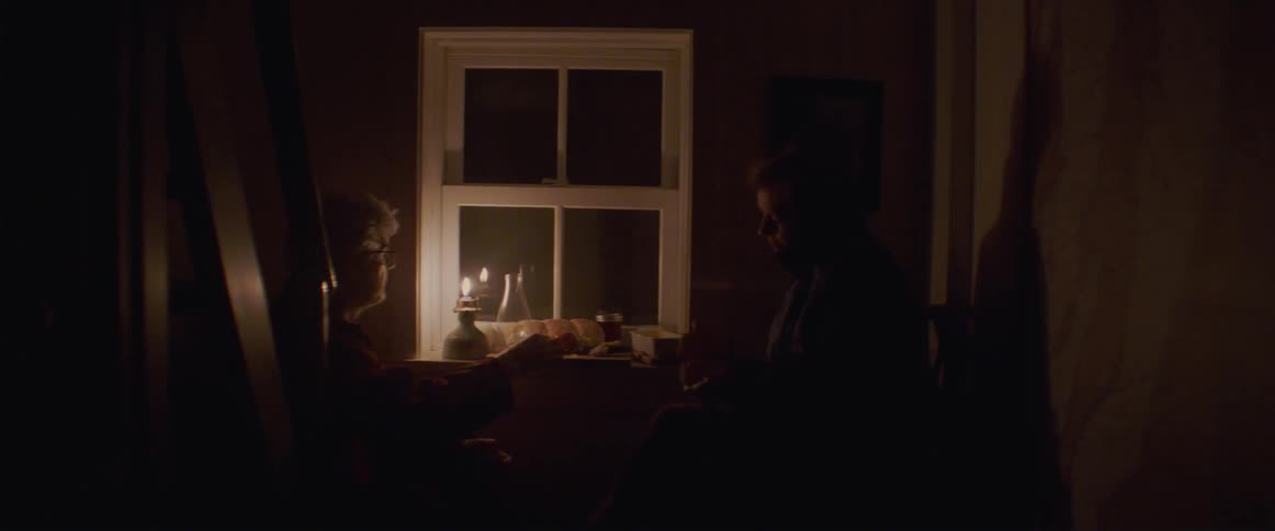 Elderly couple lighting a gas lamp while eating food on the window sill at night